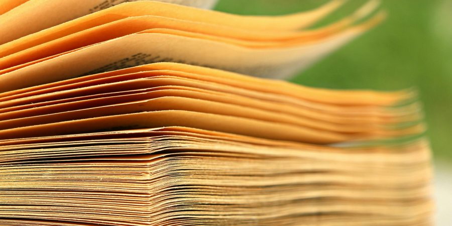 Close-up van bladzijden van een boek die bladeren in de wind tegen groene achetergrond